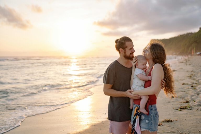 A joyful family holding each other while watching the sunset on a tropical beach.